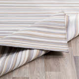 Close-up of the hand-woven Shawville Area Rug, featuring brown, gray, tan, and white stripes on a wood floor. Front