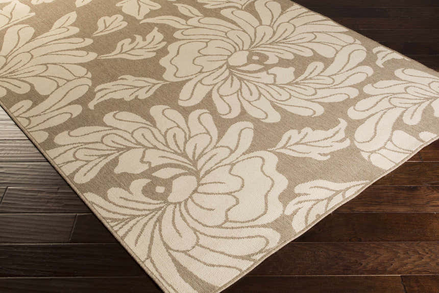 Close up of the beige Sherard Area Rug with a large floral pattern on dark wood flooring. Corner