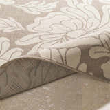 Close-up of the Sherard Area Rug showing beige floral pattern and durable machine-woven construction. Fold
