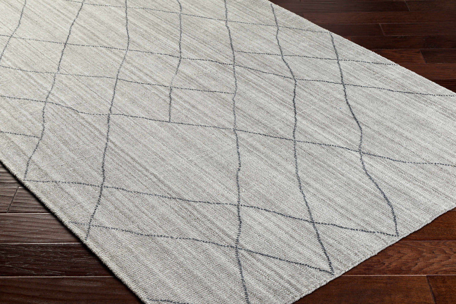 Close-up of the Nari Light Gray Area Rug. Farmhouse style rug with charcoal geometric pattern on a textured light gray background. Corner