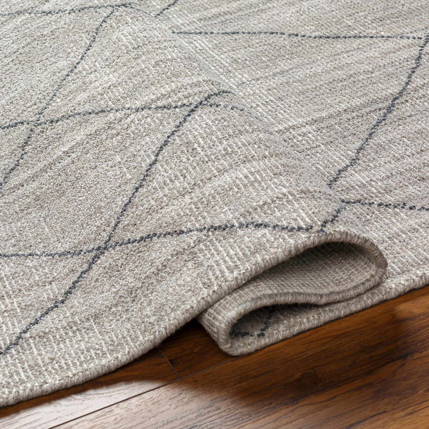 Close-up of the Nari Light Gray Area Rug showing its charcoal diamond pattern and textured cotton weave on a wood floor. Fold