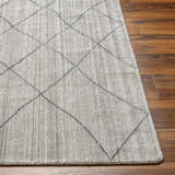 Close-up of the Nari Light Gray Area Rug showing its diamond pattern and textured weave on a dark wood floor. Front