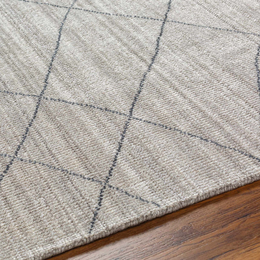 Close-up of the Nari Light Gray Area Rug showing its charcoal diamond pattern and textured cotton weave on a wood floor. Texture
