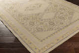 Close up of the hand knotted Shoemakersville Area Rug, beige and mustard tones, on dark wood floors. Corner