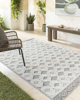 Modern patio with Salil Ivory Area Rug, woven geometric design in cream, ivory, and light gray. Rattan chair and wood bench. Roomscene-Rectangle