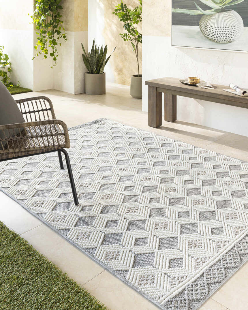 Modern patio with Salil Ivory Area Rug, woven geometric design in cream, ivory, and light gray. Rattan chair and wood bench. Roomscene-Rectangle