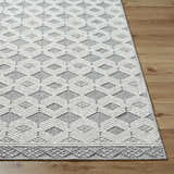 Close-up of the Salil Ivory Area Rug with a geometric diamond pattern in cream, ivory, and light gray on a wood floor. Front