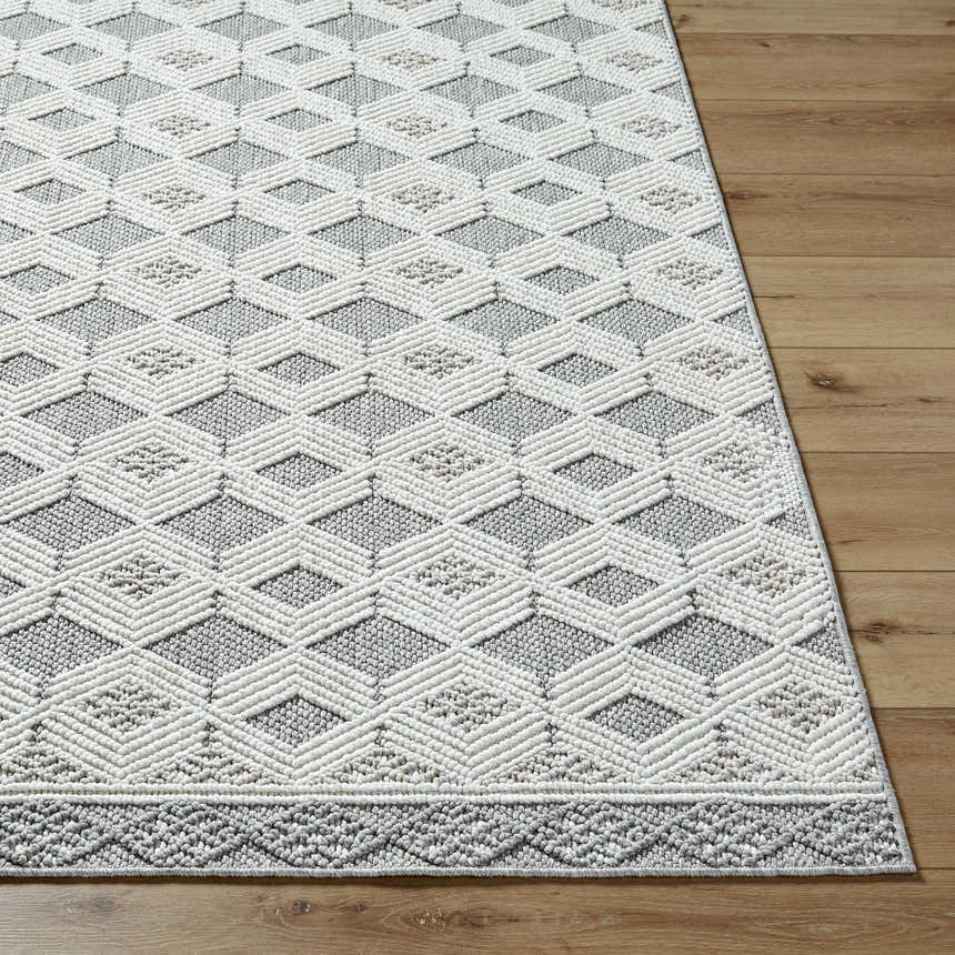 Close-up of the Salil Ivory Area Rug with a geometric diamond pattern in cream, ivory, and light gray on a wood floor. Front