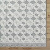 Close-up of the Salil Ivory Area Rug, showcasing its geometric diamond pattern in cream, ivory, and light gray tones. Corner