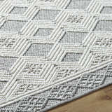 Close-up of the Salil Ivory Area Rug showing the geometric design and textured cream and light gray polyester fibers. Texture