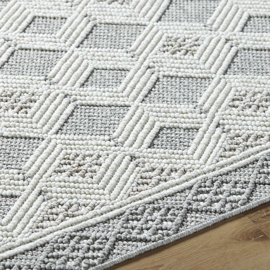 Close-up of the Salil Ivory Area Rug showing the geometric design and textured cream and light gray polyester fibers. Texture