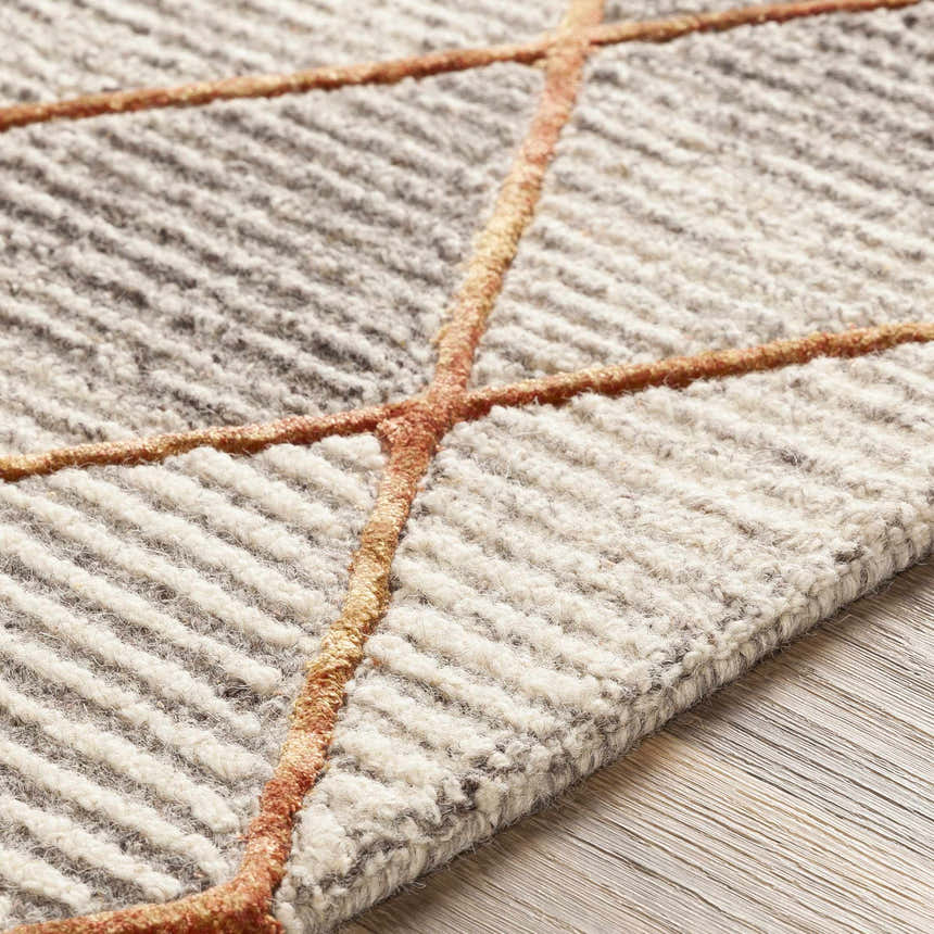 Close-up of the hand-tufted Sharpes Area Rug. Brown, mustard, and orange geometric pattern on a wool rug. Contemporary style. Texture