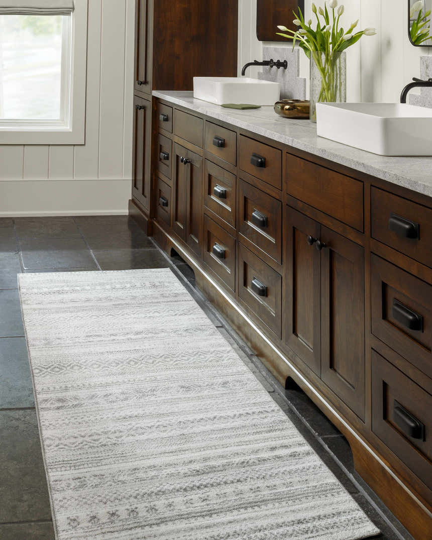 Bathroom scene with a Gizeh Silverton Washable Area Rug runner in light gray, paired with a dark wood vanity and stone tile floor. Roomscene-Runner