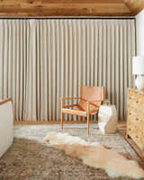 Living room scene with Ange Tan Rich Textured Traditional Rug, leather chair, and bone-colored decor. Roomscene-Rectangle