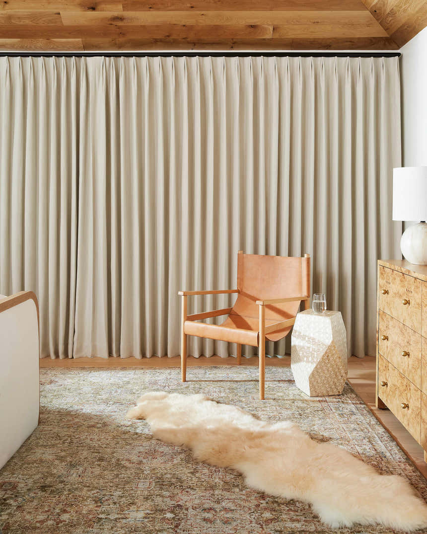 Living room scene with Ange Tan Rich Textured Traditional Rug, leather chair, and bone-colored decor. Roomscene-Rectangle