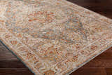 Close up of the Cress Tan Rich Textured Traditional Rug showing bone, blue, and rust colors. Corner