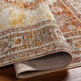 Close-up of the Moya Tan Rich Textured Traditional Rug showing bone, clay, brown, and gray tones. Rolled edge detail. Fold