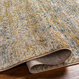 Close-up of the Sava Tan Rich Textured Rug showing bone, gold, and blue tones and the rug's texture. Fold