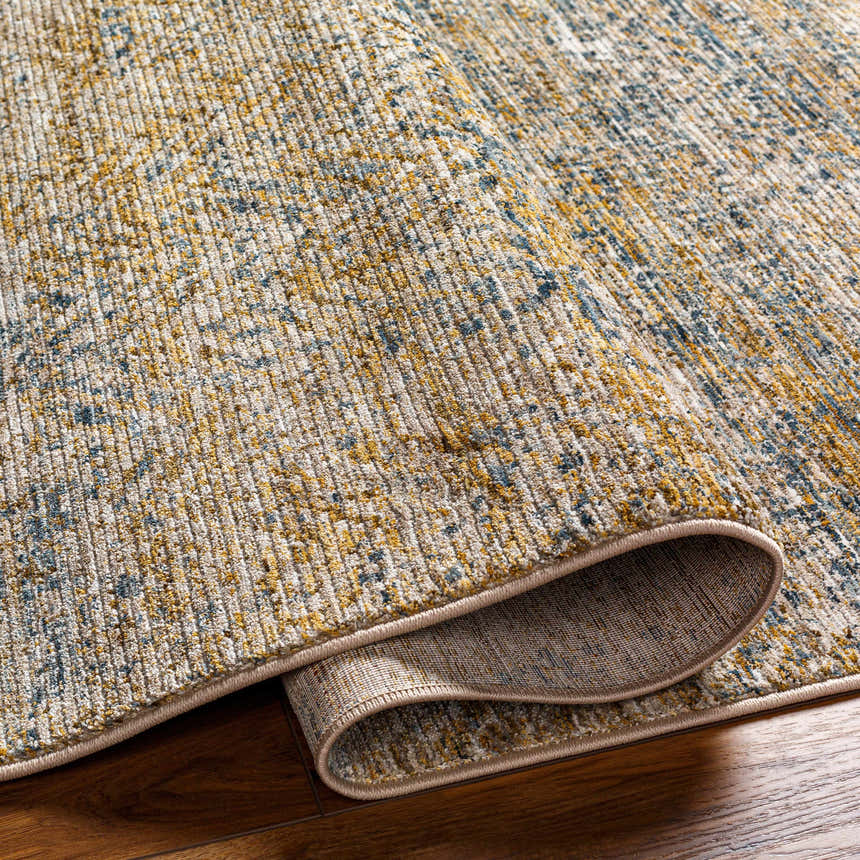 Close-up of the Sava Tan Rich Textured Rug showing bone, gold, and blue tones and the rug's texture. Fold
