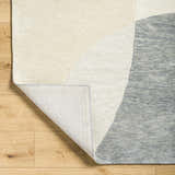 Close-up of the Cassiopeia Gray & Beige Area Rug showing the wool texture, geometric design, and backing detail. Fold
