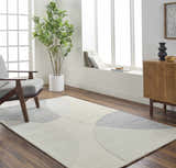 Living room scene with a gray armchair and the Cassiopeia Gray & Beige Area Rug on a wood floor. Modern, light-filled space. Roomscene-Rectangle