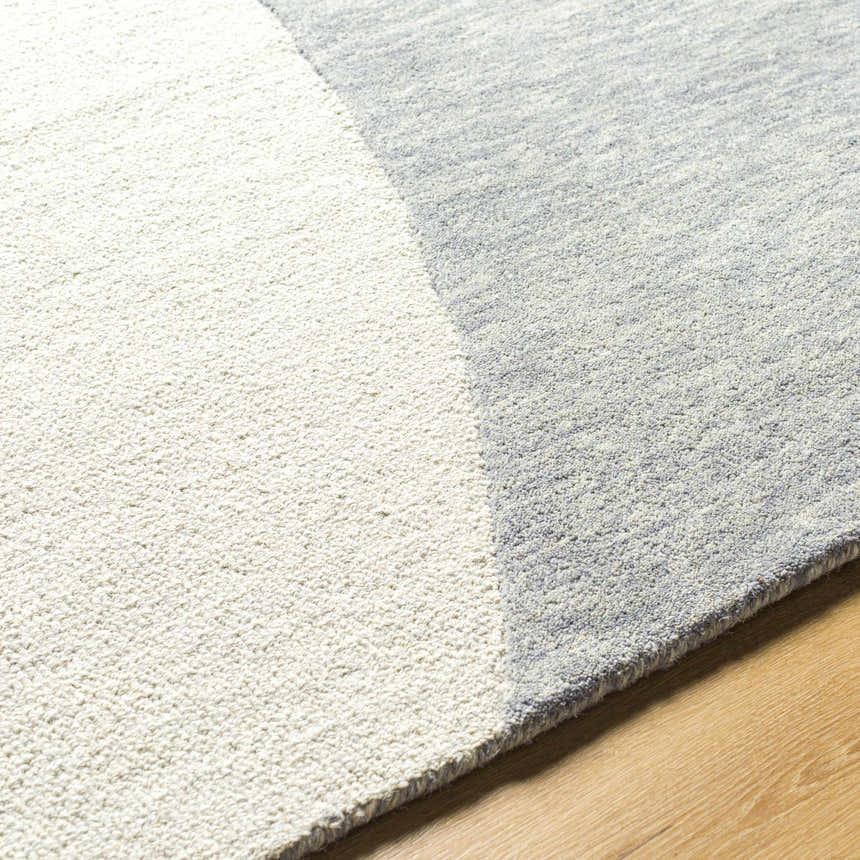 Close up of the hand-tufted Cassiopeia Gray & Beige Area Rug showing its wool texture and geometric color block design. Texture