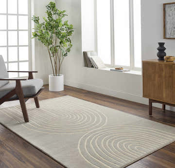 Living room scene with a gray chair and Fuat Medium Gray Area Rug featuring a beige concentric circle pattern. Roomscene-Rectangle