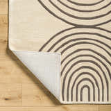 Close-up of the Fuat Beige Area Rug showing its hand-tufted wool texture and contemporary brick red and dark purple arc pattern. Fold