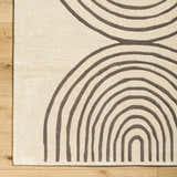 Close-up of Fuat Beige Area Rug showing its hand-tufted texture and contemporary brick red and pearl arch pattern. Corner