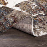 Close-up of the Silvis Boutique Area Rug showing its shag texture, burgundy, cream, blue, and mustard colors. Fold