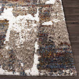 Close up of the Silvis Boutique Area Rug showing its shag texture and abstract pattern in cream, blue, and burgundy. Front