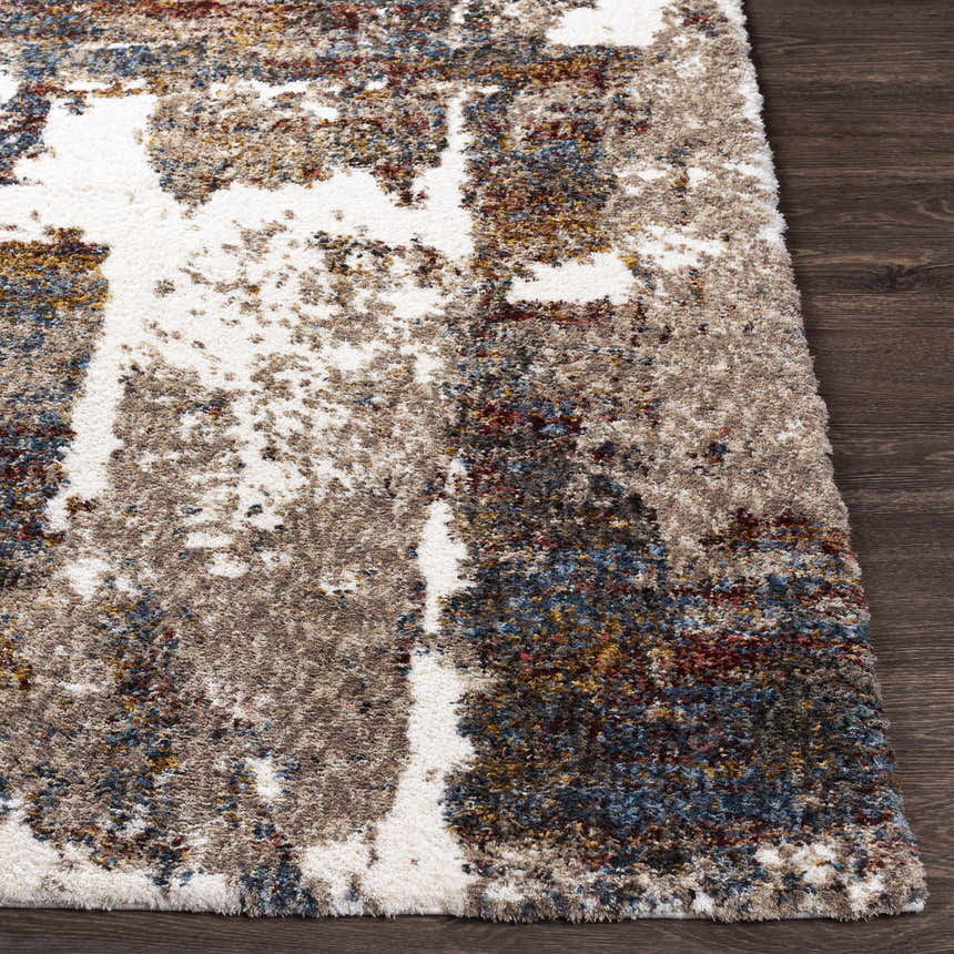 Close up of the Silvis Boutique Area Rug showing its shag texture and abstract pattern in cream, blue, and burgundy. Front
