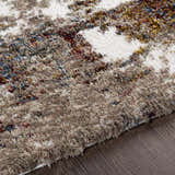 Close up of the Silvis Boutique Area Rug showing its shag texture and colors: cream, burgundy, blue, and mustard. Texture
