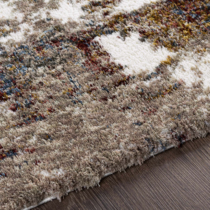 Close up of the Silvis Boutique Area Rug showing its shag texture and colors: cream, burgundy, blue, and mustard. Texture