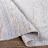 Close up of Sinai Light Blue rug showing lined pattern and wool/viscose texture. Colors are light blue, brown, and off white. Fold