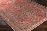 Close-up of the Siocon Washable Area Rug. Farmhouse style rug with traditional pattern in red, blue, and cream on dark wood floors. Corner