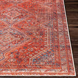 Close-up of the Siocon Washable Area Rug. Features a traditional, farmhouse design in red, blue, and white tones. Front