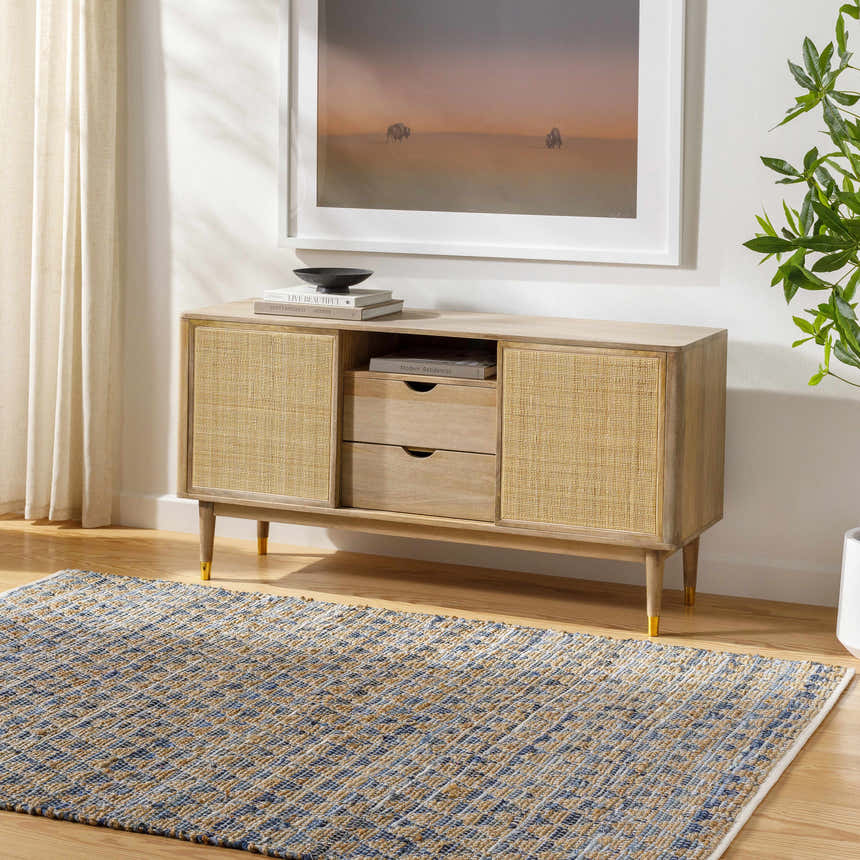 Living room scene with a Colm Recycled Blue Jean Rug, woven texture, blue and tan colors, under a wood and cane console table. Roomscene-Rectangle