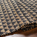 Close-up of the Colm Recycled Black Jean Rug showing its hand-woven texture and geometric black and jute pattern. Fold