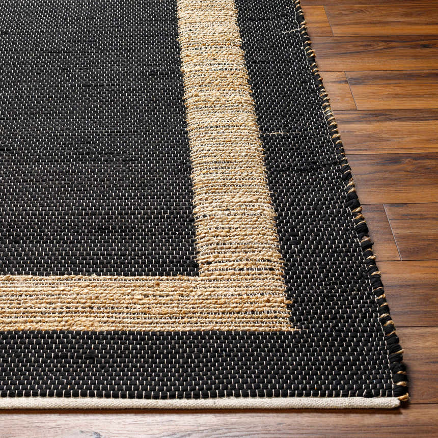 Close-up of the Ghita Black Area Rug showing a hand-woven texture and natural border on a wood floor. Front