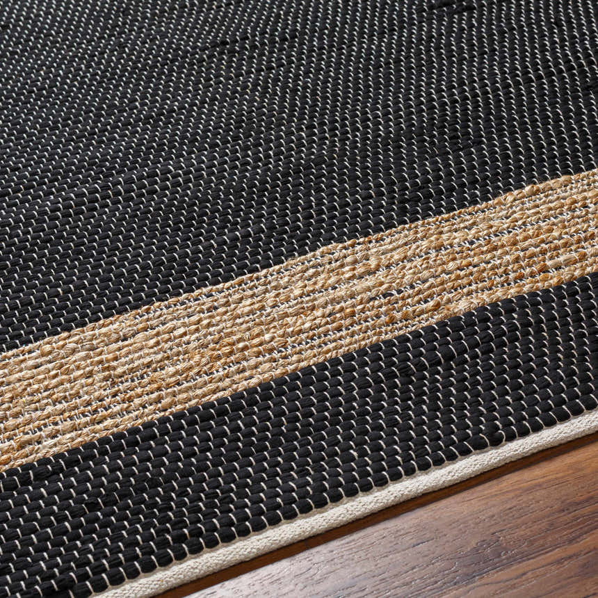 Close-up of the hand woven Ghita Black Area Rug showing its texture and natural fiber stripe detail. Texture