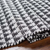 Close-up of hand woven Gzifa Jute Rug. Black and white contemporary rug with a textured, geometric pattern. Fold