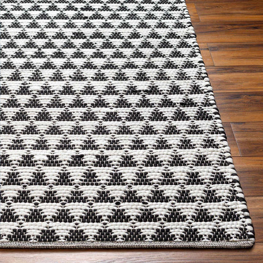 Close-up of the hand woven Gzifa Jute Rug. The rug has a contemporary black and beige geometric pattern. Front