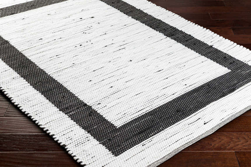 Close-up of the hand woven Jaden Area Rug. Charcoal and off white jute and recycled fabric create a contemporary design. Corner
