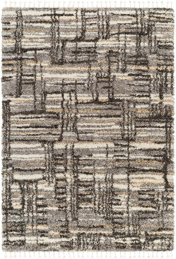Close-up of the Arne Area Rug, a shag rug with a geometric pattern in charcoal, gray, taupe, and off-white. Tassels on the edge. Design-Rectangle-537
