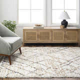 Living room scene with a Hersz Cream Area Rug, gray chair, and wood cabinet. Neutral tones and natural light. Roomscene-Rectangle