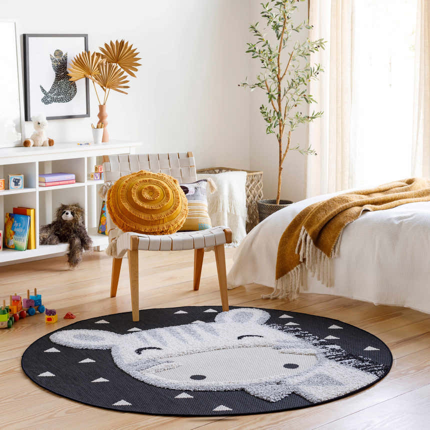 Kids room scene with a round Giraffe Bowtie Animal Print Nursery Area Rug, chair, toys, and neutral decor. Roomscene-Round