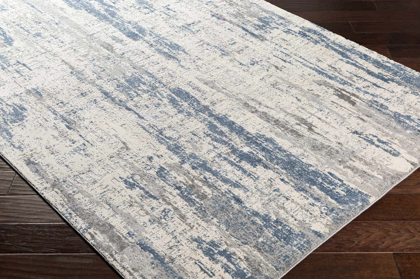 Close-up of Skidby Area Rug in blue, charcoal, gray, and off-white. Contemporary style with abstract pattern. Corner