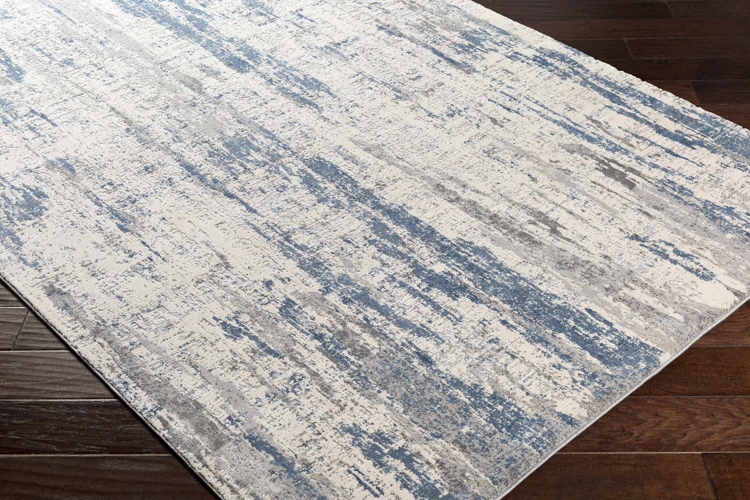 Close-up of Skidby Area Rug in blue, charcoal, gray, and off-white. Contemporary style with abstract pattern. Corner