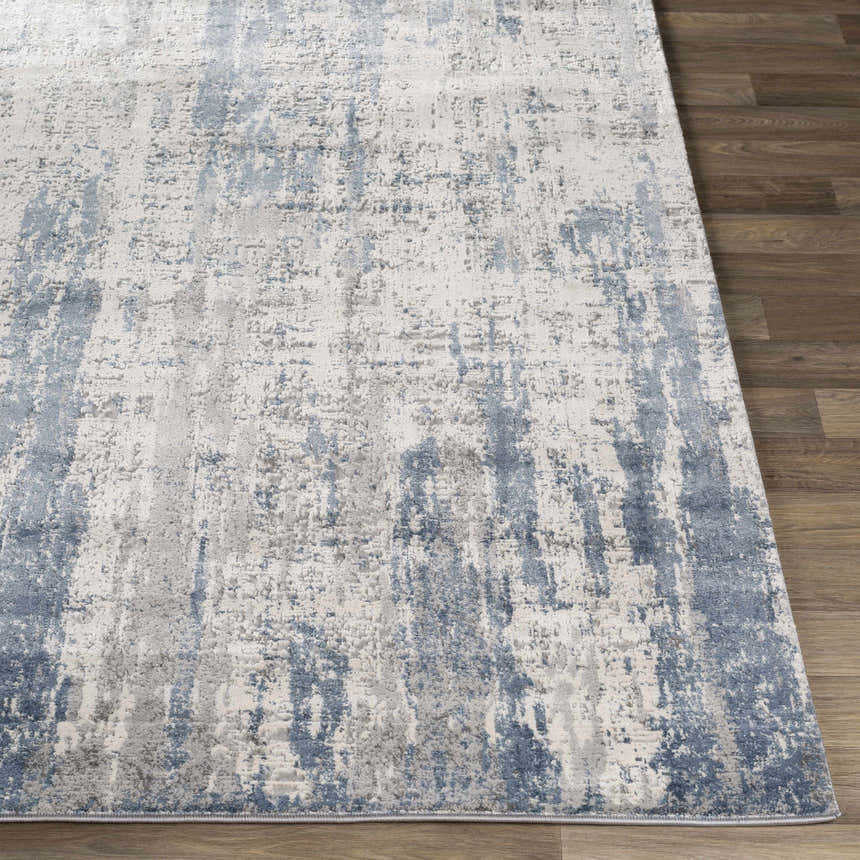 Close-up of Skidby Area Rug. Blue, charcoal, and gray abstract pattern on an off-white base. Contemporary style. Front